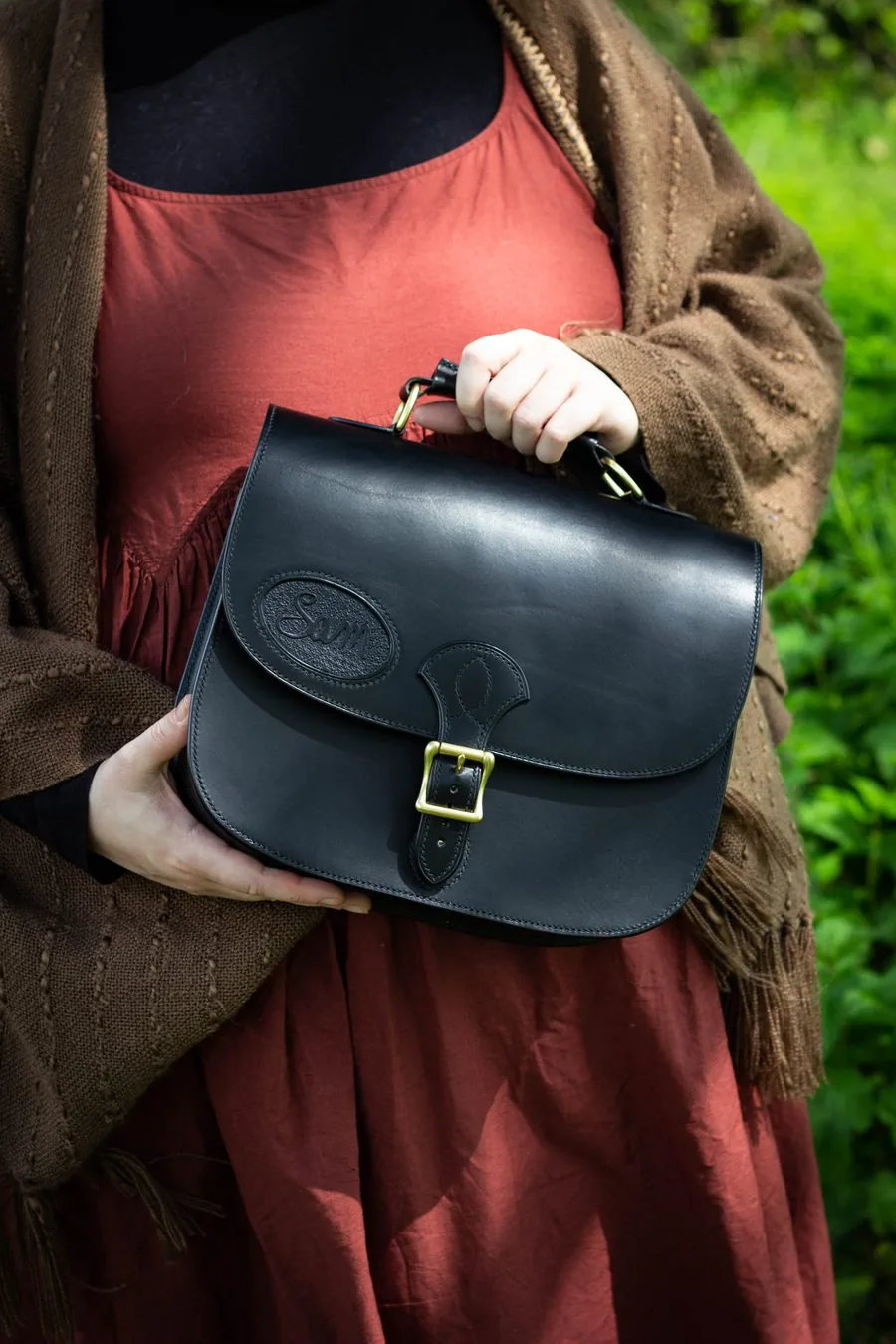 Cartable en cuir noir à boucle en laiton, tenu à deux mains