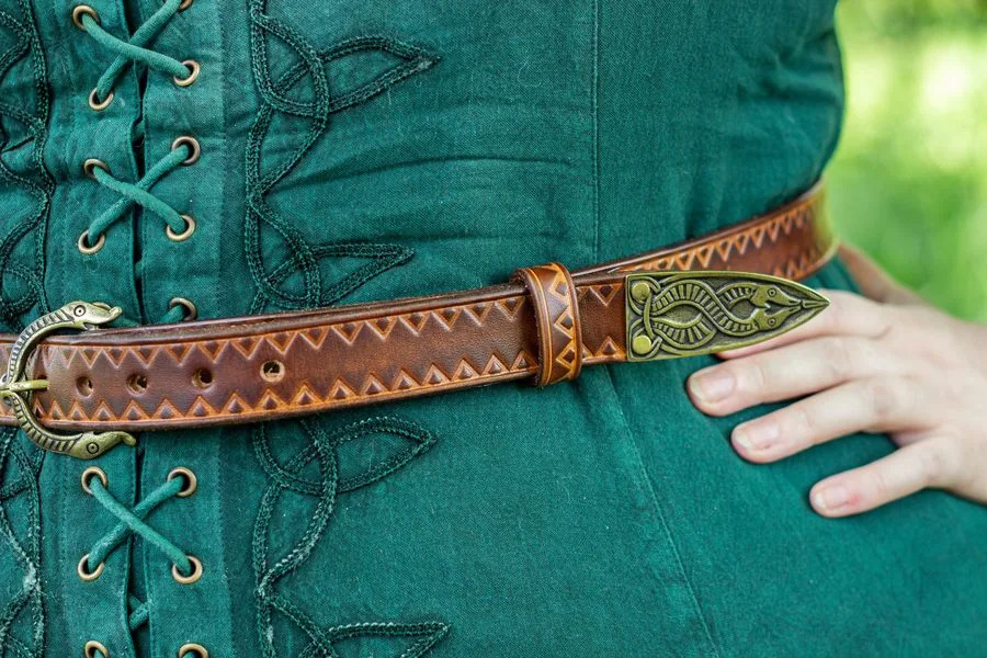 Ceinture gravée de chevrons, boucle et bout en laiton ouvragés, portée sur une robe verte