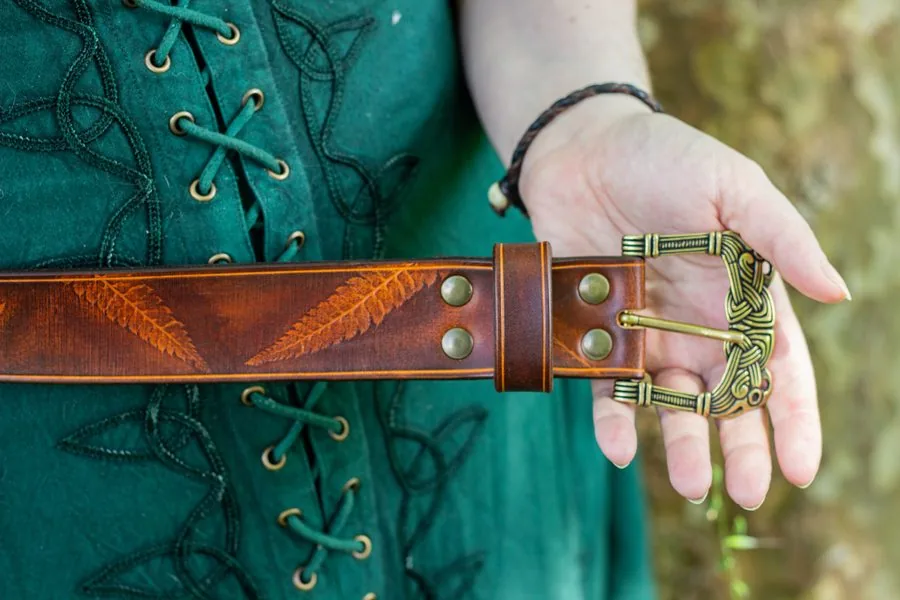 Ceinture gravée de fougères à boucle en laiton ouvragée, tenue sur une robe verte