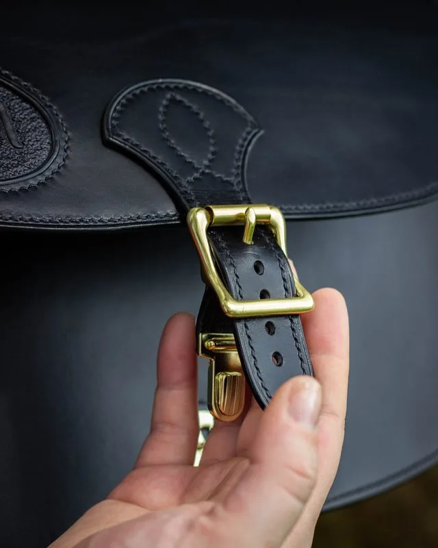 Détail d'un sac en cuir noir cousu au point sellier, avec sa boucle en laiton