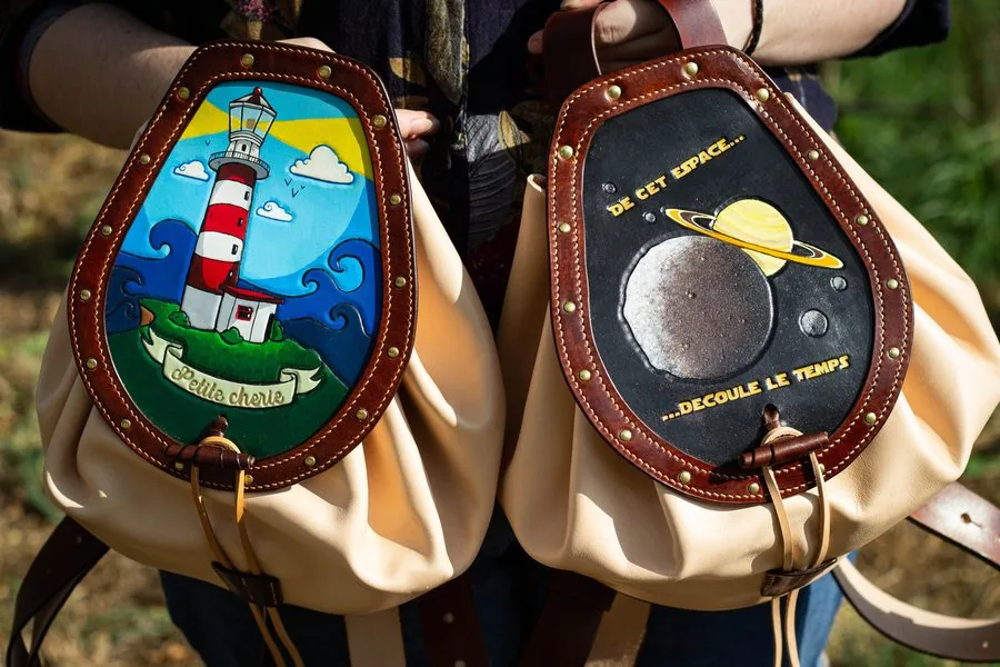 Deux sacs à dos à cordon en cuir clair, médaillons peints d'un phare et d'une planète