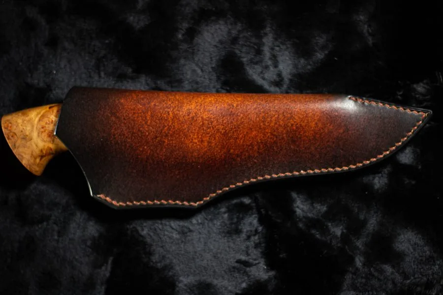 Étui en cuir teinté en dégradé, couteau rangé, sur fond noir