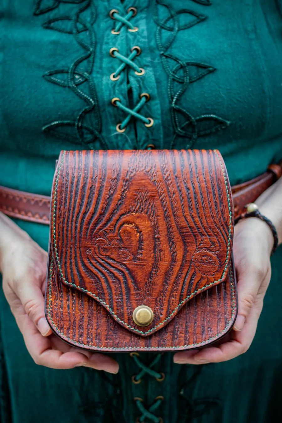 Sacoche de ceinture repoussée d'un motif de veinage de bois, tenue à deux mains