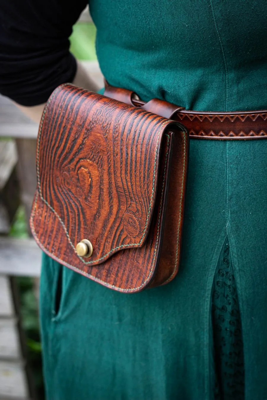 Sacoche de hanche repoussée d'un motif de veinage de bois, portée à la ceinture sur une robe verte