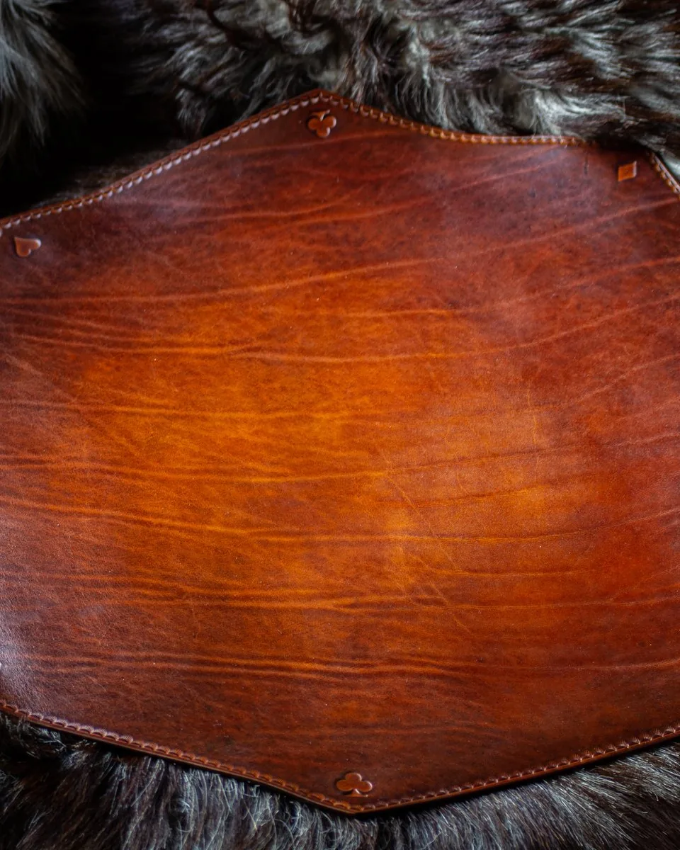 Tapis de jeu octogonal en cuir teinté brun, cousu sur le pourtour et marqué aux angles des symboles pique, cœur, carreau et trèfle, posé sur une fourrure